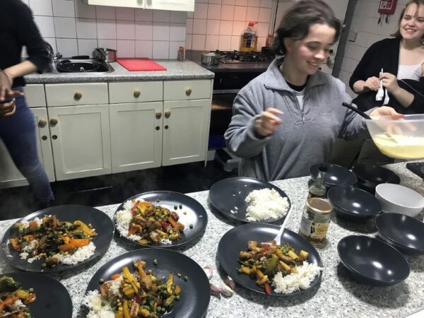 A teenager taking part in cooking a group meal