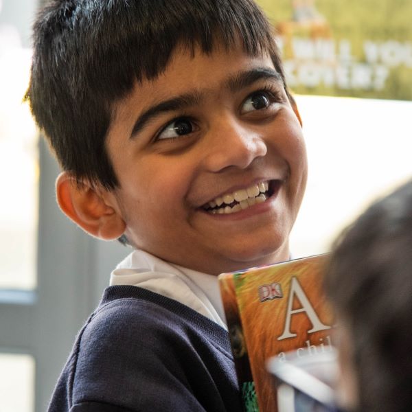 A young boy who looks very excited, holding his new book from The Children's Book Project