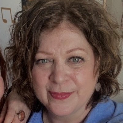 Angie, a white woman in her early 60s with brown hair and a big smile.