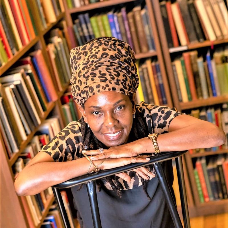 A beautiful Black woman, smiling and wearing a traditional headscarf.