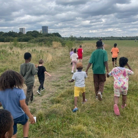 Group of primary-age children outside, seen from the back.