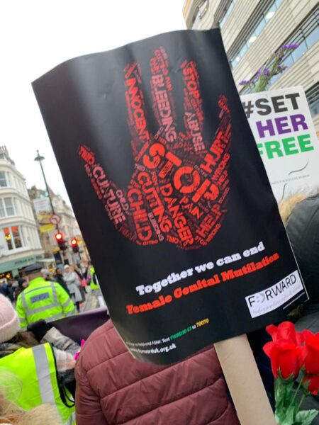 Placard showing a hand and the words Together w can end Female Genital Mutilation. 