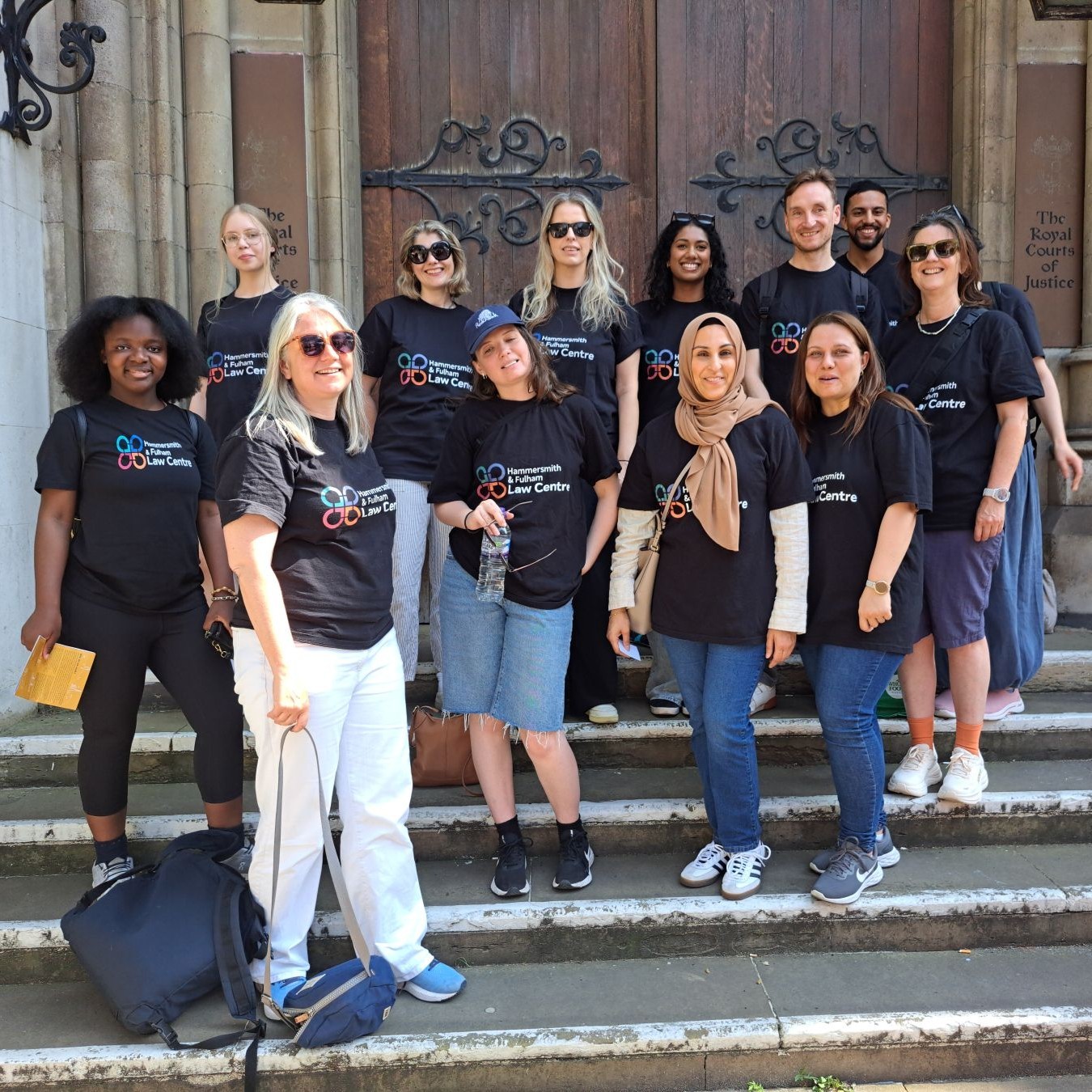 A group of women standing on the steps of the Royal Court of Justice. They are wearing t-shirts saying Hammersmith Law Society.