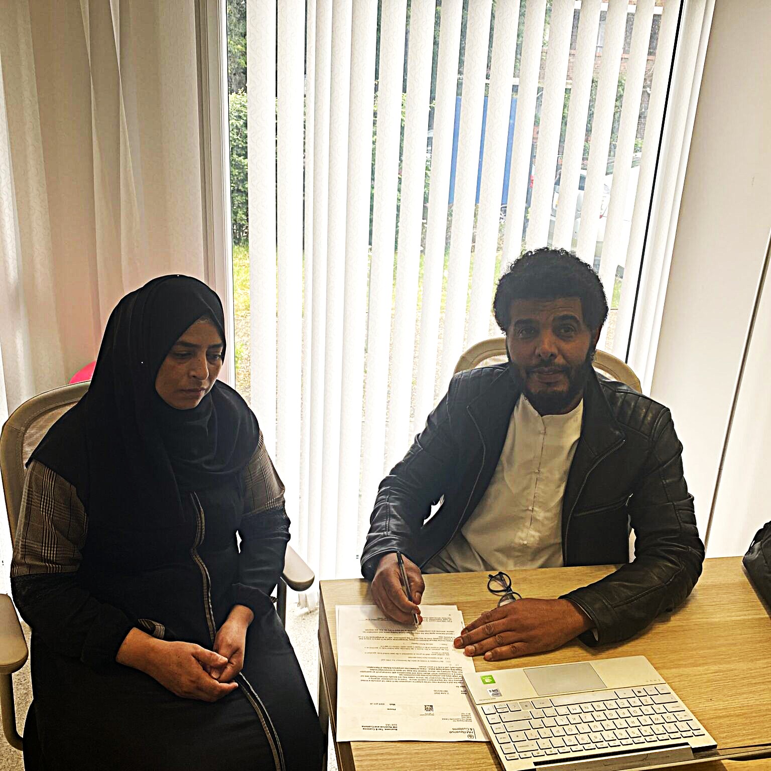 Jamal from Somali Parents sits at a table with a woman, who is wearing a headscarf.