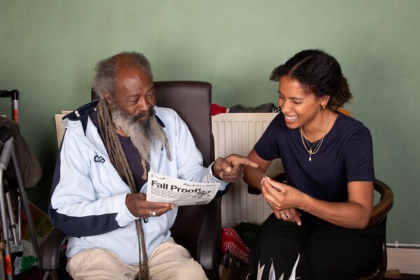 An older man and a younger female volunteer. Both are smiling.